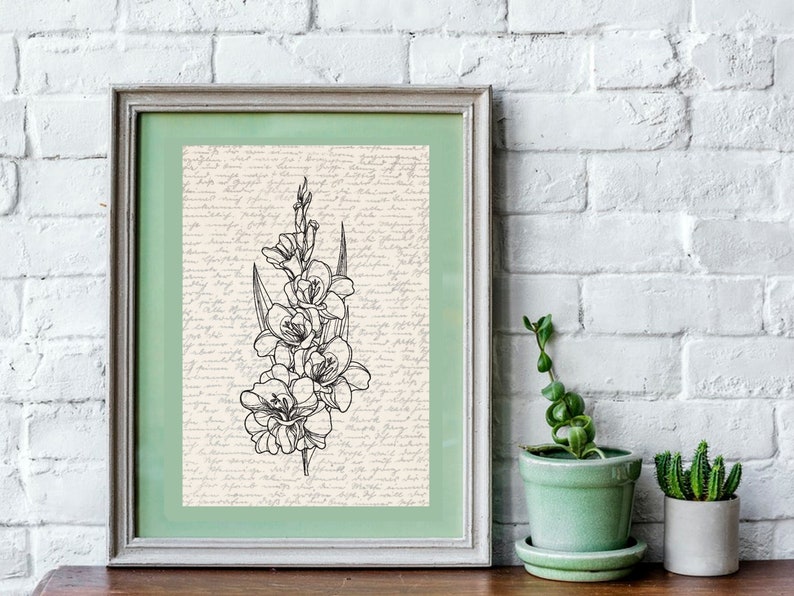 May include: A framed black and white line drawing of a flower with a green mat and a white frame. The background of the drawing is a cream color with black script writing.
