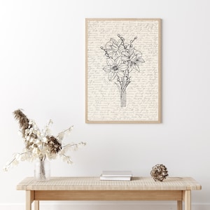 May include: A black and white line drawing of a bouquet of daffodils on a cream background with handwritten text. The drawing is framed in a light wood frame.