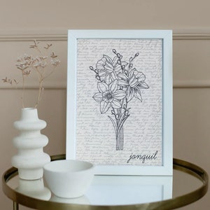 May include: A white framed print with a black and white line drawing of a bouquet of jonquils. The background is a cream color with a handwritten script. The word "jonquil" is written in black at the bottom of the print.