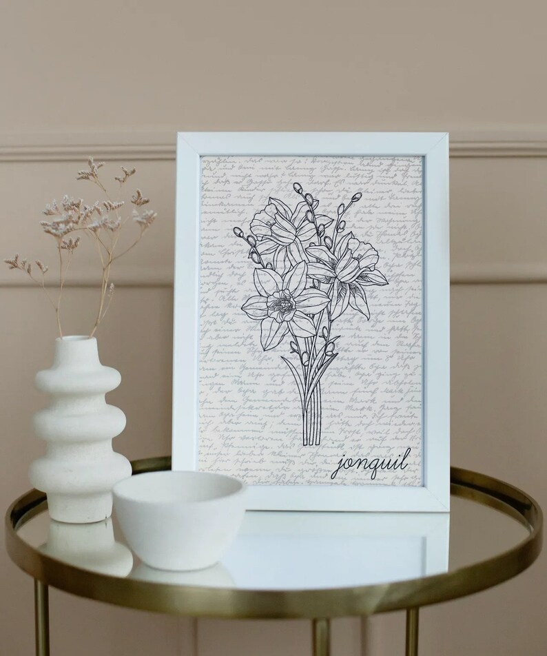 May include: A white framed print with a black and white line drawing of a bouquet of jonquils. The background is a cream color with a handwritten script. The word "jonquil" is written in black at the bottom of the print.