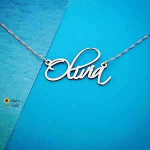 May include: Silver necklace with the name "Olivia" written in cursive script.