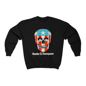 May include: Black sweatshirt with a red, white, and blue skull graphic and the text "Hunter S. Thompson" printed below.