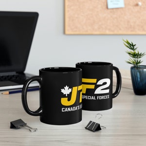 Può includere: Due tazze in ceramica nere con un design grafico bianco e giallo. Il design presenta il testo "JF2 SPECIAL FORCES" e una bandiera canadese. Il testo "CANADA'S ELITE" è incluso anche su una delle tazze.