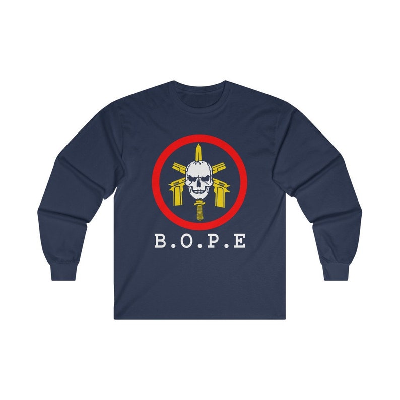 May include: Navy blue long-sleeve shirt featuring a circular emblem with a skull, guns, and a knife, surrounded by a red ring. The text "B.O.P.E" is printed in white below the emblem. The shirt is made of a soft material.