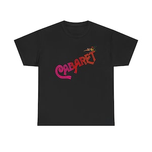 Peut inclure: T-shirt noir avec un graphisme "Cabaret" rose et rouge. Le texte est souligné de points blancs.