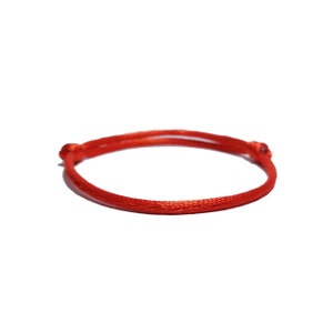 May include: A red string bracelet with a simple knot design.
