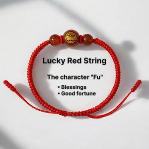 May include: A red string bracelet with a central brown bead featuring a gold design, flanked by two smaller brown beads. The bracelet is knotted and has the text "Lucky Red String" and "The character 'Fu' - Blessings - Good fortune."