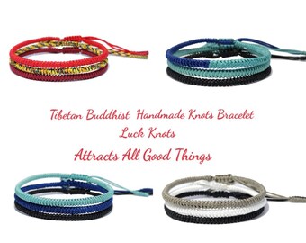 May include: Four Tibetan Buddhist handmade knot bracelets in red, blue, green, and white. The bracelets are made with three strands of cord and feature intricate knot patterns. The text "Tibetan Buddhist Handmade Knots Bracelet Luck Knots Attracts All Good Things" is displayed below the bracelets.