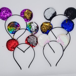 Pode incluir: Conjunto de orelhas de faixa de cabeça com lantejoulas coloridas. As faixas de cabeça são pretas e as orelhas são de várias cores, incluindo vermelho, azul, verde, dourado, prateado e roxo.