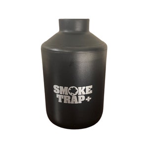 May include: A black cylindrical bottle with a silver logo that reads "SMOKE TRAP+" on the front.