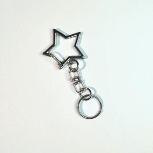 May include: A silver star-shaped keychain with a silver chain and a silver ring.