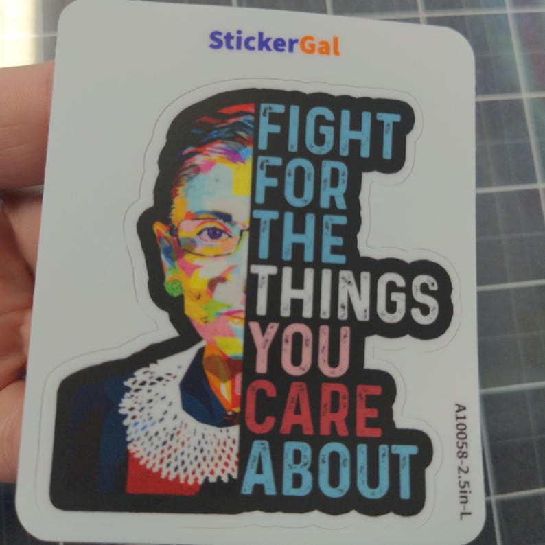 May include: A rectangular sticker featuring a colorful pop-art style portrait of Ruth Bader Ginsburg on the left and the text "FIGHT FOR THE THINGS YOU CARE ABOUT" in bold, multi-colored block letters on the right. The sticker measures 2.5 inches.