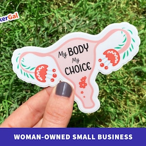 May include: A die-cut sticker shaped like a uterus in light pink with the black text "My Body My Choice" printed in the center. The design features decorative red floral accents with green leaves on both sides of the fallopian tubes.