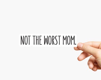 May include: A rectangular white sticker featuring the black text NOT THE WORST MOM. in a simple sans-serif font. The sticker has a clean white border around the lettering, creating a clear and legible design for application on various surfaces.