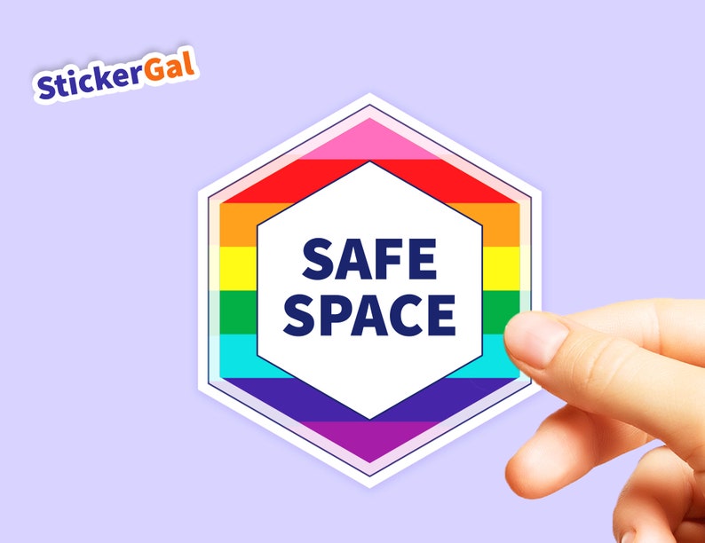 May include: A hexagonal sticker with a rainbow border and the words "SAFE SPACE" in a white hexagon in the center.