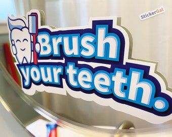 May include: A die-cut vinyl sticker featuring a cartoon tooth character holding a red toothbrush with blue toothpaste. The text reads Brush your teeth in bold blue and white letters with a dark blue outline. A small StickerGal logo is in the corner.