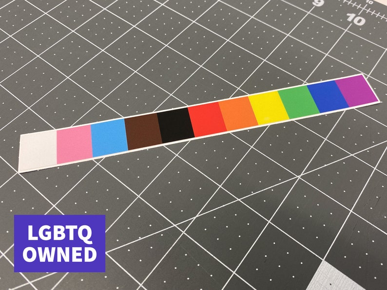 May include: A rectangular sticker with a color gradient representing the LGBTQ+ Pride flag. The sticker features a white, pink, light blue, brown, black, red, orange, yellow, green, dark blue, and purple color scheme. The text "LGBTQ OWNED" is in a blue rectangle.