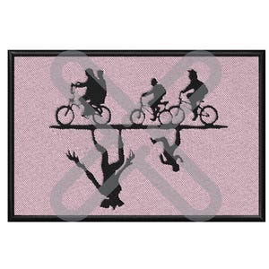 Puede incluir: Parche bordado con siluetas de personas en bicicleta sobre una figura reflejada. El diseño es negro sobre fondo rosa con borde negro. El parche es rectangular, para ropa o accesorios.