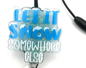 May include: A blue and white glitter badge holder with a black lanyard and a clear retractable badge reel. The badge holder features the text "Let it snow somewhere else".