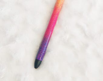 May include: A glitter pen with a gradient design. The pen transitions from orange to pink to purple. The pen has a silver tip and a black tip.