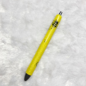 May include: A yellow glitter pen with a black bee design.