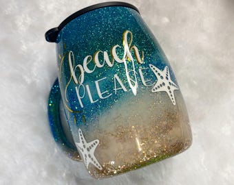 May include: Glitter-covered travel mug with a blue and gold ombre design. The mug features the words "beach PLEASE" in gold and white, along with white starfish accents. The mug has a black lid and a handle.
