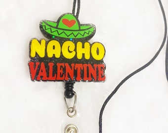 May include: A black lanyard with a red, yellow, and green glitter badge holder that says "Nacho Valentine" with a small red heart on a green sombrero.
