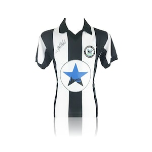 May include: A black and white striped soccer jersey with a blue star and the Newcastle United Football Club logo. The jersey is signed "Gazza".