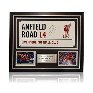 Könnte beinhalten: Ein gerahmtes Schild in Schwarz und Silber mit dem Text "Anfield Road L4 Liverpool Football Club" und einem roten Wappen des Liverpool Football Club. Das Schild ist von Stefan Bajcetic signiert und enthält zwei Fotos von ihm beim Fußballspielen.