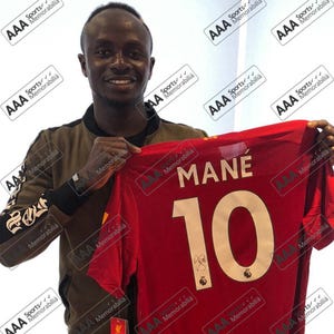 May include: A red football shirt with the name "MANE" and the number "10" on the back. The shirt is signed by the player.