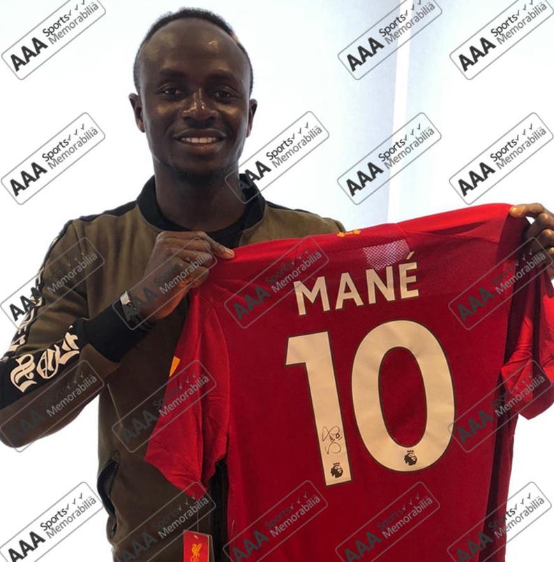 May include: A red football shirt with the name "MANE" and the number "10" on the back. The shirt is signed by the player.