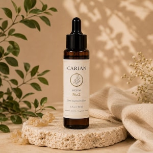 Puede incluir: Un frasco cuentagotas de vidrio marrón con tapa negra y etiqueta color crema. La etiqueta dice CARIAN, RESIN No.2, Time Suspension Elixir y 1.7 oz / 50 ml. El frasco es cilíndrico con cuello estrecho y un tapón de goma negro en la parte superior.