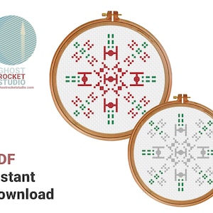 May include: Two embroidery hoop patterns for cross stitch. The top pattern is red and green and the bottom pattern is gray and green. Both patterns feature a snowflake design with a star wars inspired symbol in the center.
