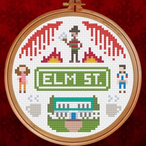 May include: A cross-stitch embroidery hoop with a green sign that reads "ELM ST." surrounded by a red and yellow pixelated image of Freddy Krueger from the movie A Nightmare on Elm Street.