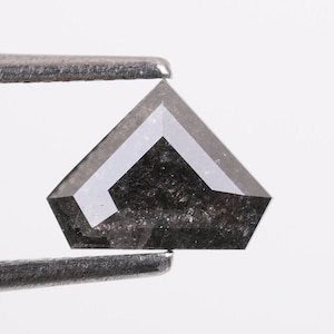 May include: A dark gray, faceted, pentagon-shaped diamond held by tweezers.