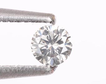 May include: A clear round diamond held by tweezers.