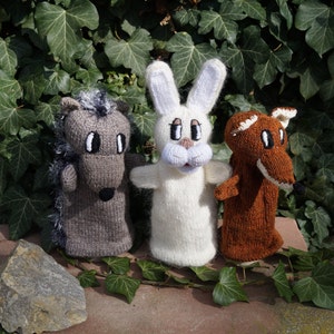 Könnte beinhalten: Drei gestrickte Fingerpuppen: ein graues Pferd, ein weißes Kaninchen und ein brauner Fuchs. Das Pferd hat eine schwarze Nase und eine graue Mähne. Das Kaninchen hat lange Ohren und eine rosa Nase. Der Fuchs hat eine weiße Brust und eine schwarze Nase.