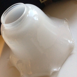 May include: White glass lampshade with a ruffled edge. The shade is opaque and has a smooth, glossy finish.