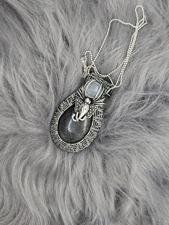 Silver sheen obsidian wrapped in sterling silver wire with elephant charm and white moonstone accent. **Sterling silver chain included.