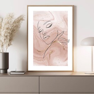 Puede incluir: Un dibujo de l&iacute;nea de la cara de una mujer con los ojos cerrados sobre un fondo de m&aacute;rmol rosa y dorado.