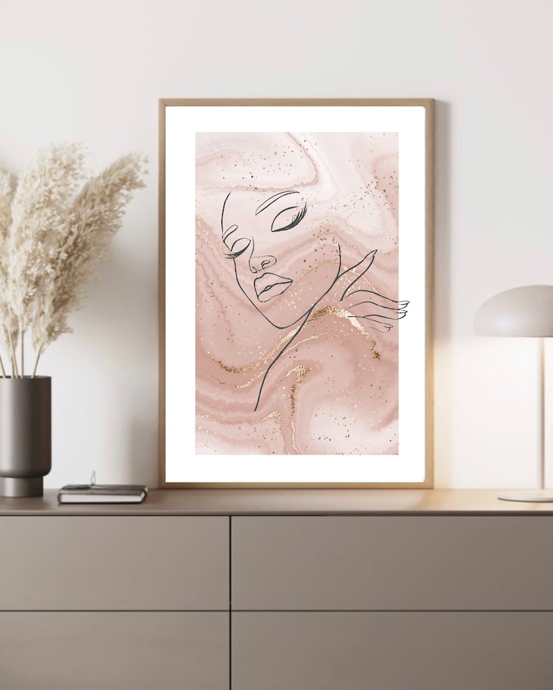 Puede incluir: Un dibujo de l&iacute;nea de la cara de una mujer con los ojos cerrados sobre un fondo de m&aacute;rmol rosa y dorado.