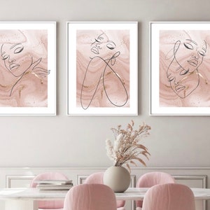 Puede incluir: Tres impresiones enmarcadas con un fondo de m&aacute;rmol rosa y dibujos de l&iacute;nea negra de rostros de mujeres. Las impresiones est&aacute;n en marcos blancos y est&aacute;n colgadas en una pared blanca.