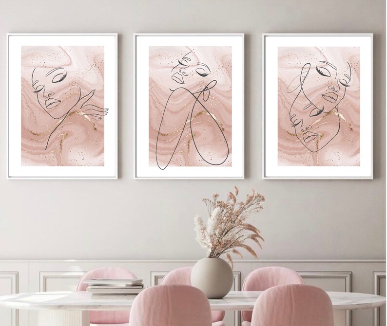 Puede incluir: Tres impresiones enmarcadas con un fondo de m&aacute;rmol rosa y dibujos de l&iacute;nea negra de rostros de mujeres. Las impresiones est&aacute;n en marcos blancos y est&aacute;n colgadas en una pared blanca.
