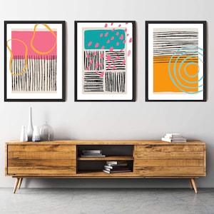May include: Three framed abstract art prints with black and white stripes, geometric shapes, and pops of pink, teal, orange, and yellow.