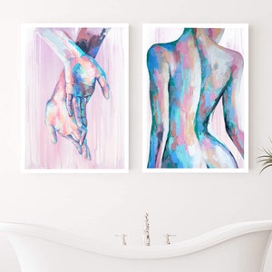 Puede incluir: Dos pinturas abstractas en marcos blancos. La pintura de la izquierda muestra un par de manos en tonos de rosa, azul y verde. La pintura de la derecha muestra una vista posterior del torso de una persona en tonos de rosa, azul y verde.
