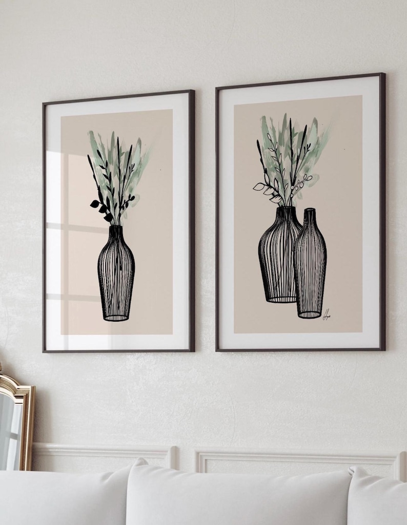 May include: Two framed art prints featuring black line drawings of vases with greenery. The vases have a striped design and are filled with green and black foliage against a beige background. The frames are dark brown.