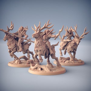 May include: Three miniature figurines of elves riding stag-like creatures. The elves are holding weapons and are posed in a dynamic fashion. The figures are painted in a light brown colour and are set on circular bases.