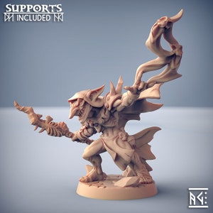 May include: A detailed miniature figurine of a goblin wizard, holding a staff with a skull at the top. The goblin is wearing a cloak and has a menacing expression. The figurine is painted in a light brown colour.