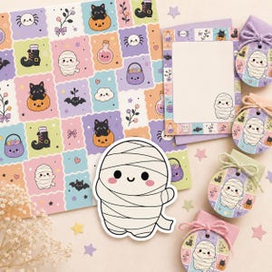 May include: A collection of stationery items featuring a repeating pattern of pastel-colored squares with illustrations of mummies, black cats in pumpkins, bats, spiders, and potion bottles, including a large mummy sticker and circular gift tags.
