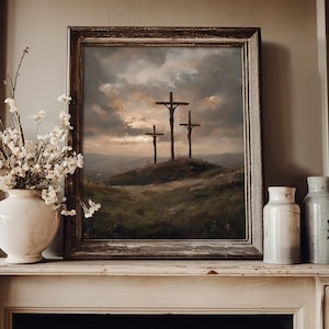 May include: A framed painting depicts three crosses on a hill under a dramatic sky. The artwork is in a rustic, wooden frame, and is displayed on a white mantelpiece. A white vase with floral arrangements and two ceramic jars are also on the mantel.